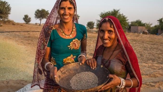 Two female farmers in India holding a bowl of guar.