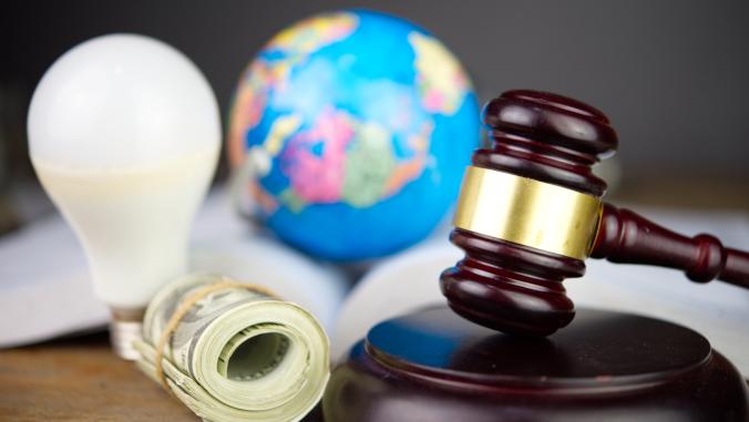 A light bulb, roll of cash, a globe, and a gavel placed next to one another