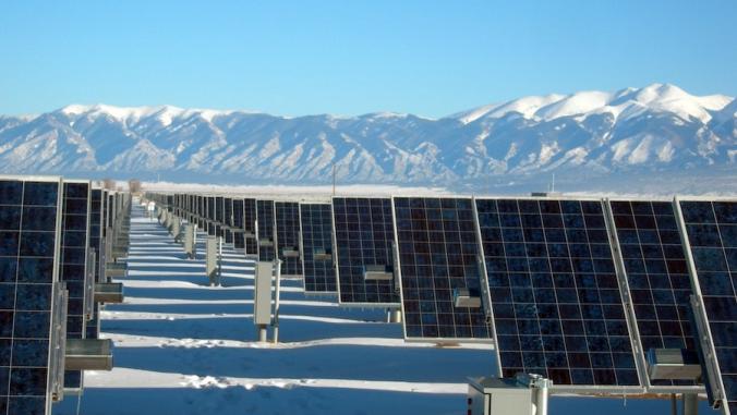 A picture of rows of solar panels in the middle of snowy mountain peaks.